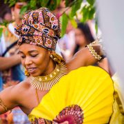 Dançarina afro-brasileira usando trajes coloridos e joias durante uma celebração cultural.