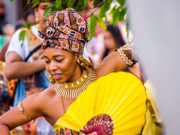 Dançarina afro-brasileira usando trajes coloridos e joias durante uma celebração cultural.