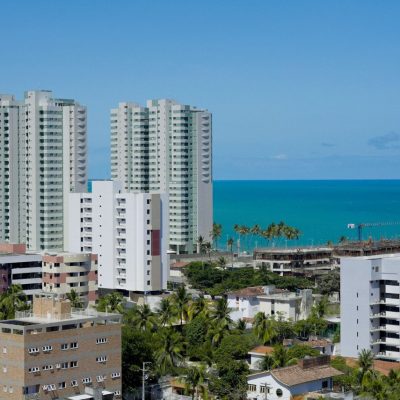 Vista de edifícios de Maceió ao longo da faixa litorânea, sob céu claro.