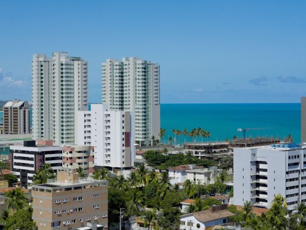 Vista de edifícios de Maceió ao longo da faixa litorânea, sob céu claro.