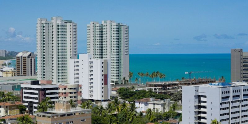 Vista de edifícios de Maceió ao longo da faixa litorânea, sob céu claro.