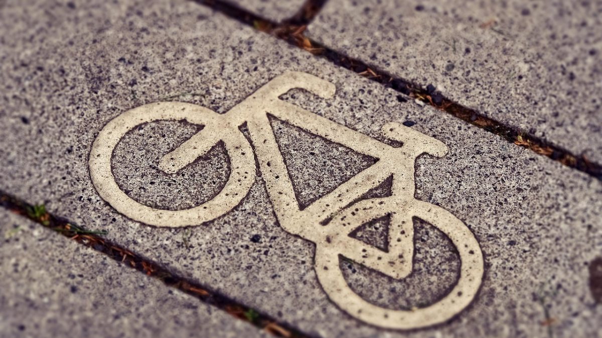 Sinalização de ciclovia com símbolo de bicicleta em uma via urbana.